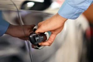 Close-up of a person's hand pulling a dark car door handle, illustrating how much should it cost to unlock a locked car.