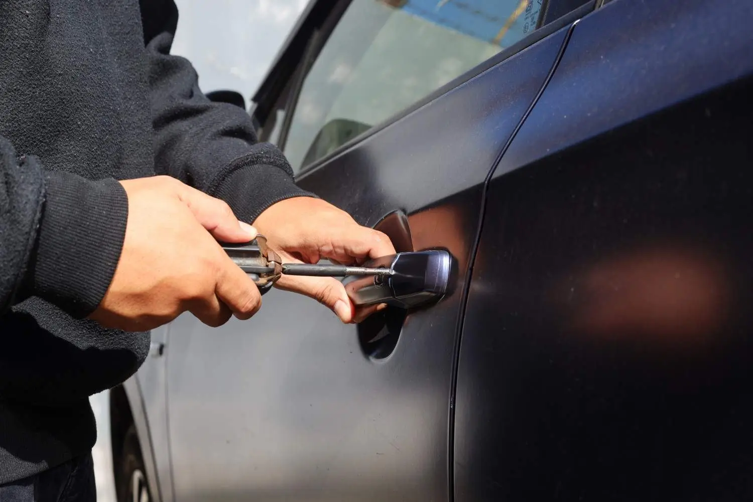 Close-up of a person's hand pulling a car door handle, illustrating how to spot a lockout scam before you pay.